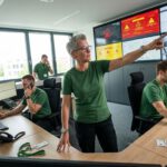 In der modernen Leitstelle für Alarmverfolgung 2026 koordinieren mehrere Mitarbeitende Telefongespräche, Kamerabilder und Alarme an großen Monitorwänden.