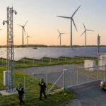 Windpark und Photovoltaik-Feld mit umzäuntem Zugang, Sicherheitsfahrzeug und zwei Sicherheitsmitarbeitern in NRW
